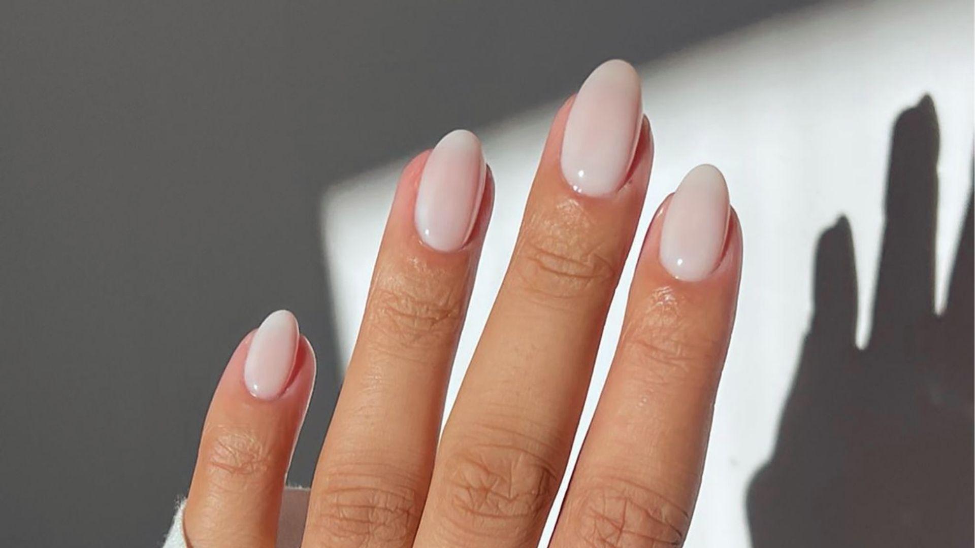 Short oval dip nails in sheer glossy milky pink for a minimalist clean girl nail aesthetic.
