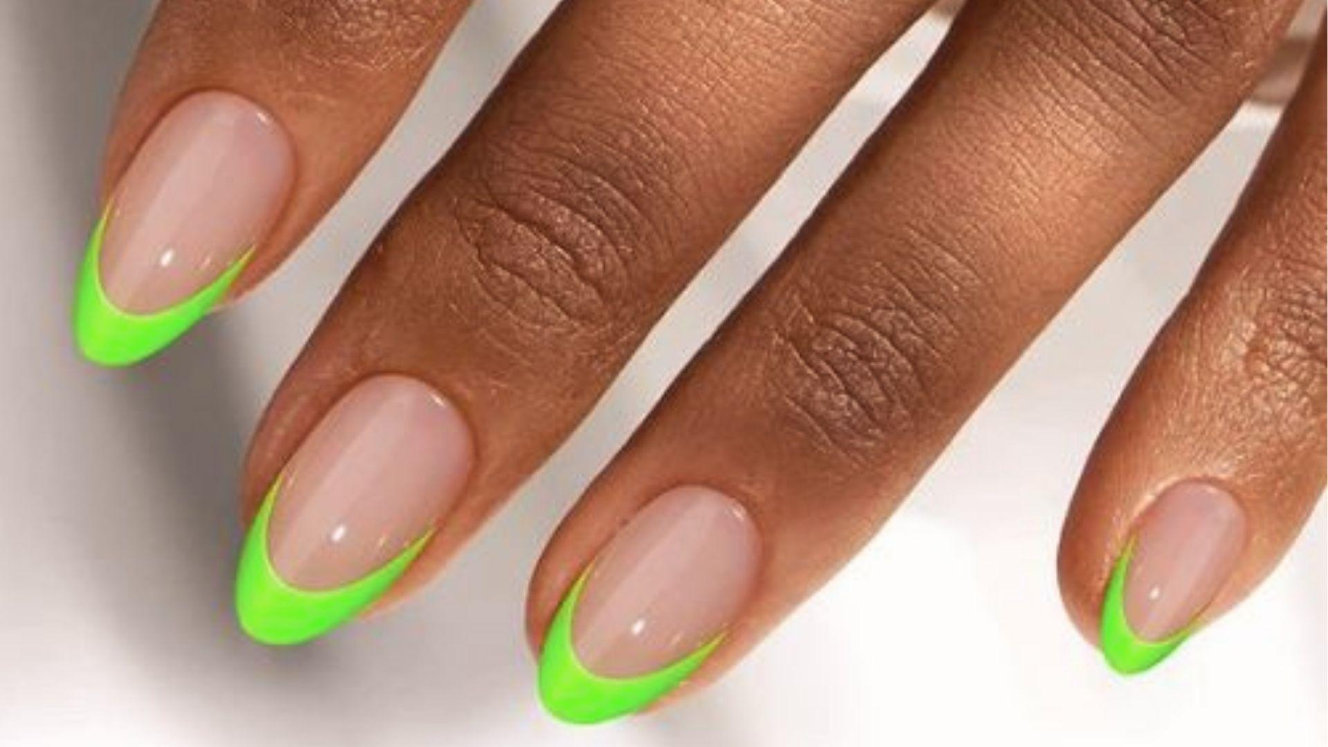 Almond dip nails with sheer nude base and neon green French tips for a bold summer manicure look.
