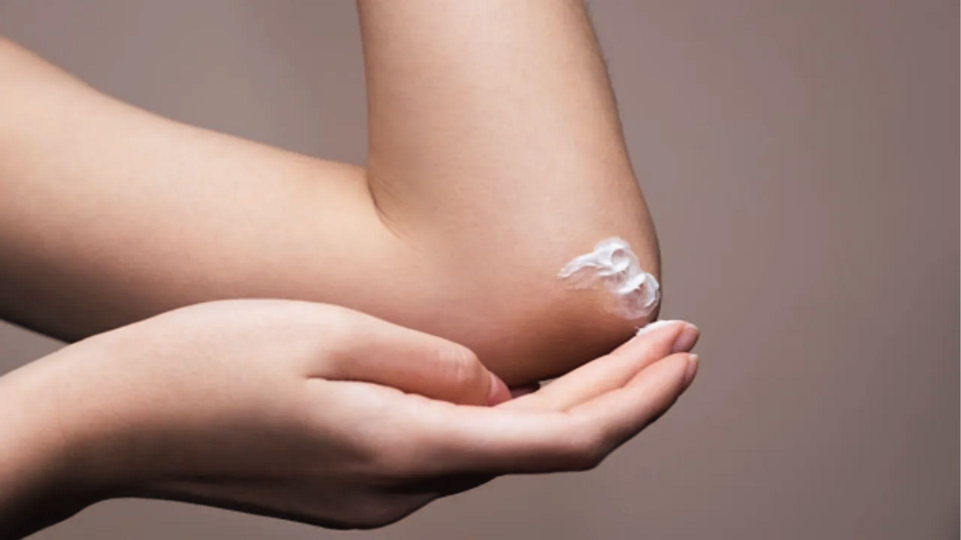 Close-up of hands applying tanner to elbow.