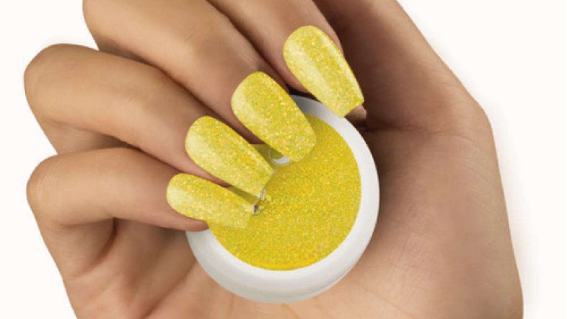 Nails with chunky neon yellow glitter polish, hand holding matching glitter powder jar