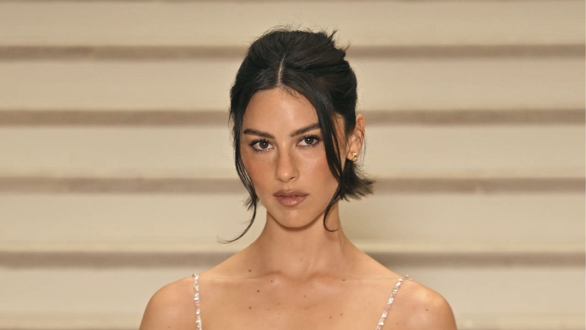 Runway half up half down black hairstyle with center part, messy top twist, and soft face framing