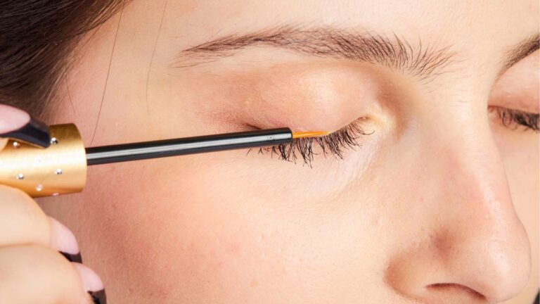 Girl applying eyelash serum to upper lash line with applicator brush