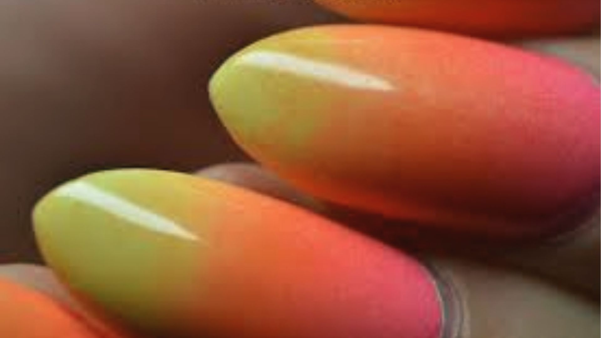 Ombre almond nails fading from neon yellow to orange to pink, glossy summer gradient closeup