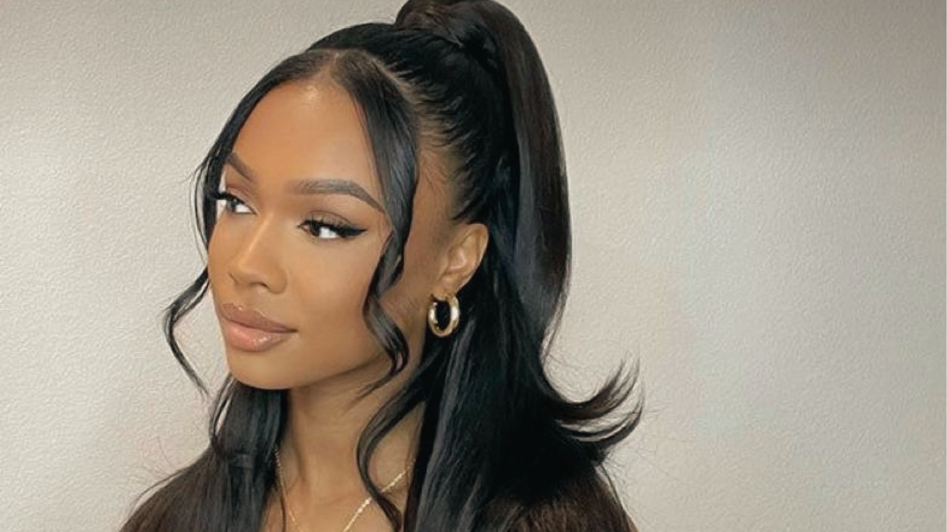 High messy half up half down ponytail on wavy black hair with statement earrings indoors
