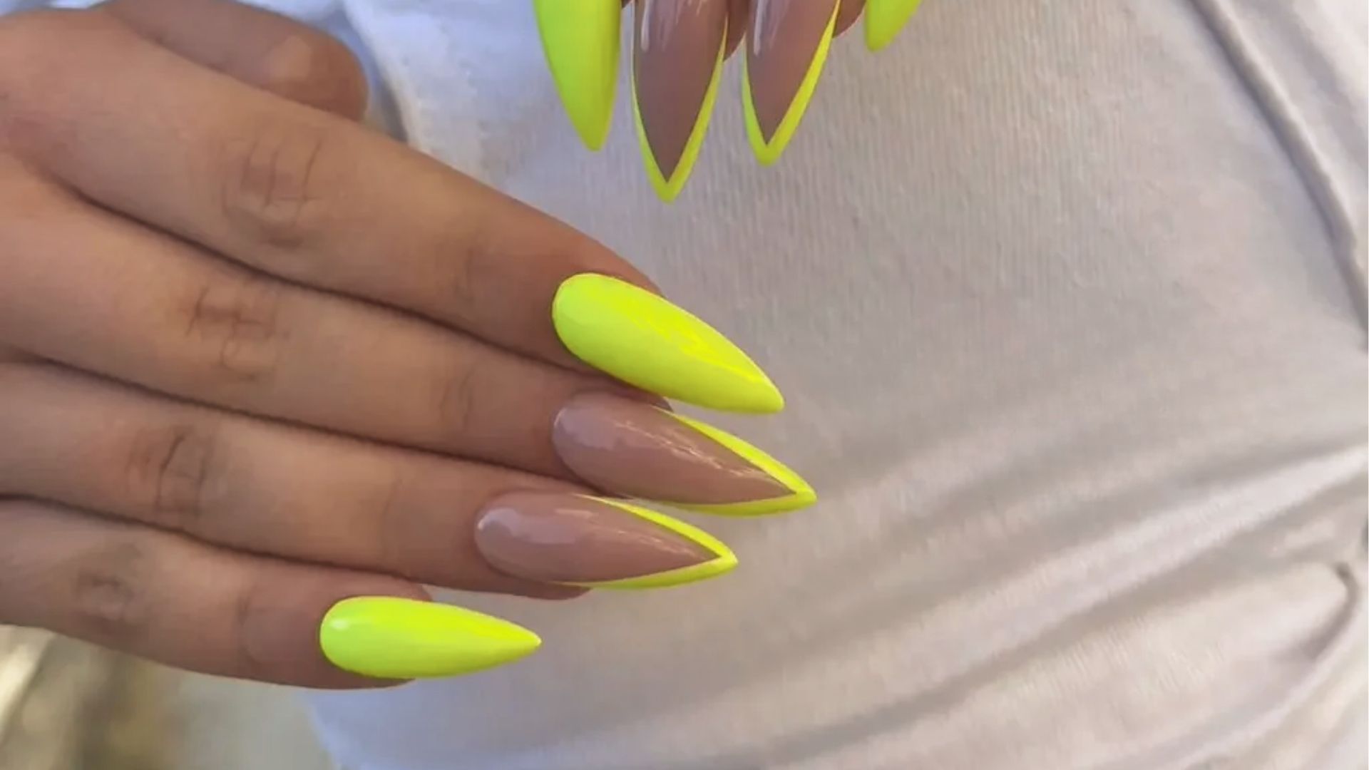 Almond nails with wave design and solid neon yellow, bold pointed shapes on white tee