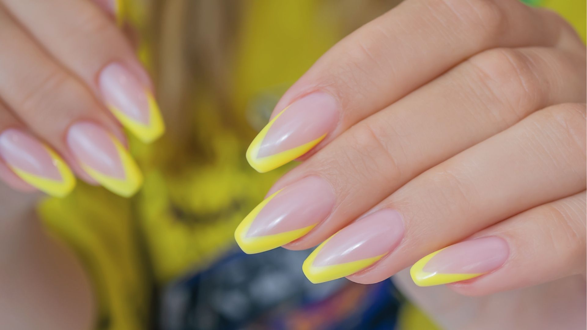 Long almond nails with neon yellow double French tips on nude base, styled with gold jewelry