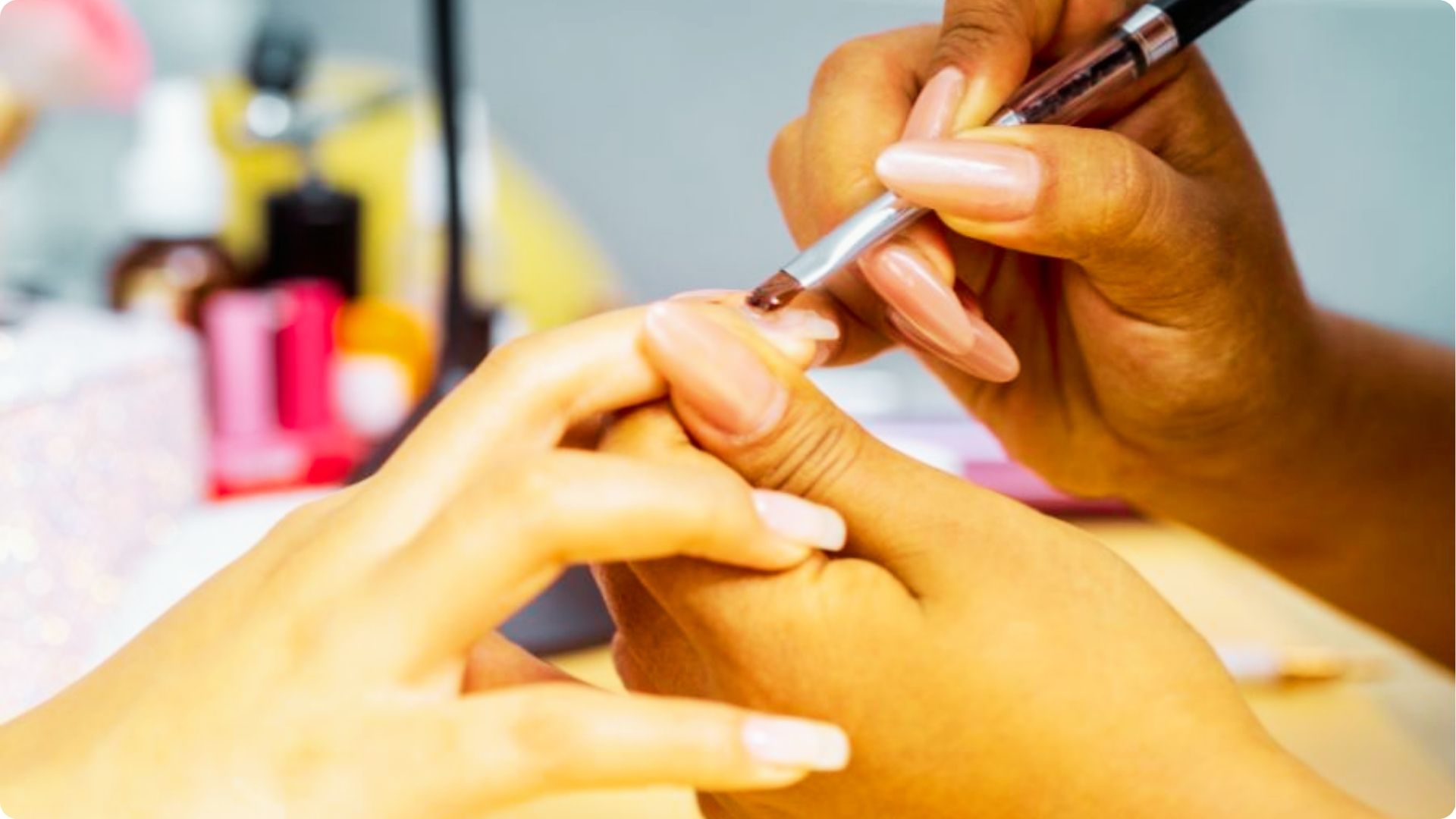 A nail technician uses a fine brush to apply Manicure Gel to the cuticle area of a client’s fingernail.