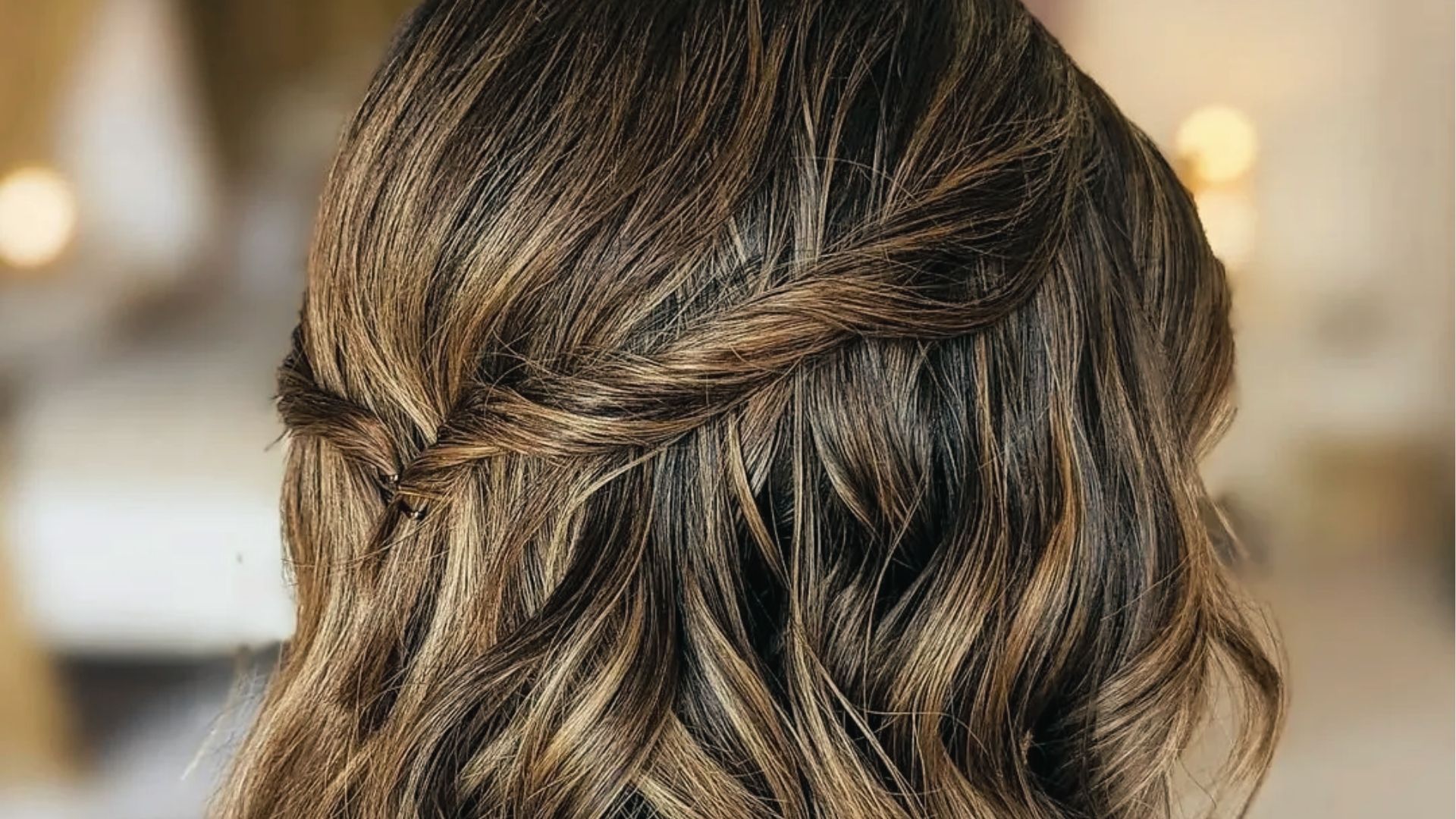 Twisted half up half down black hairstyle with crisscross braided detail and voluminous soft waves