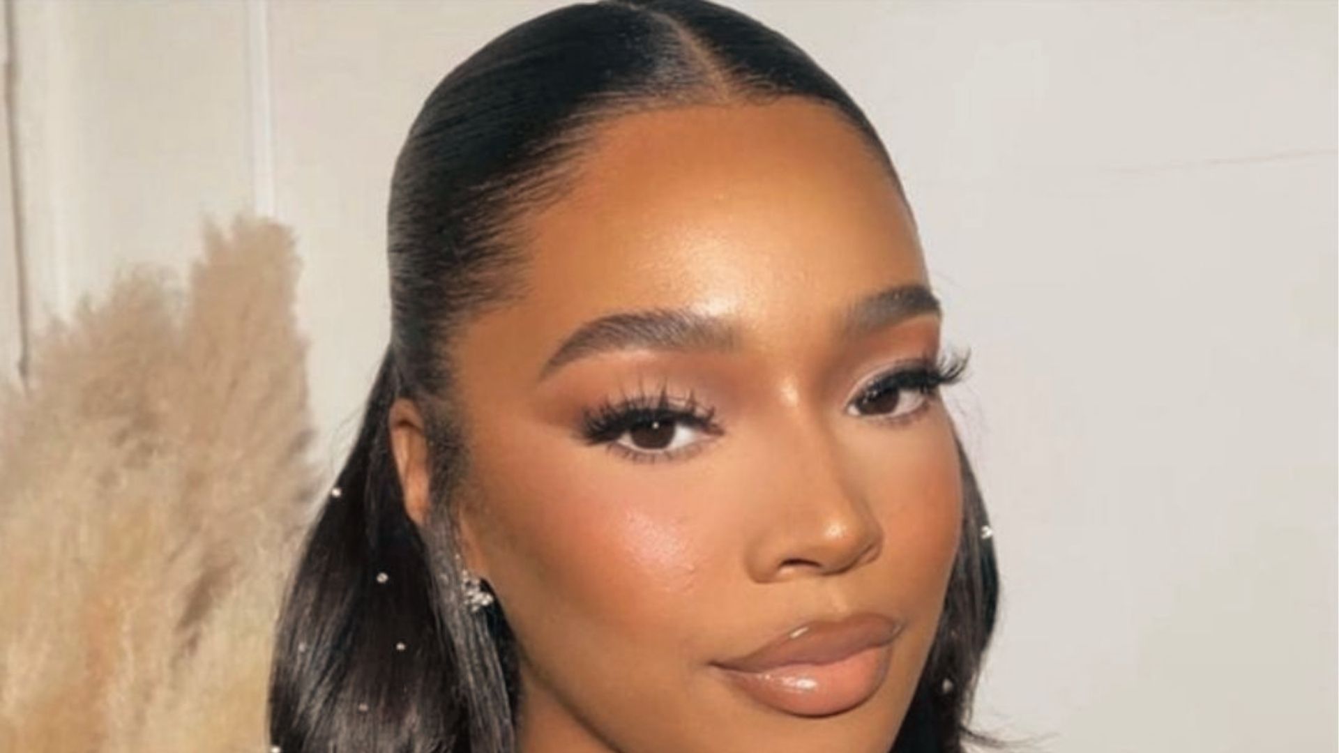 Chic half up half down style on layered black hair with soft waves and curtain bangs