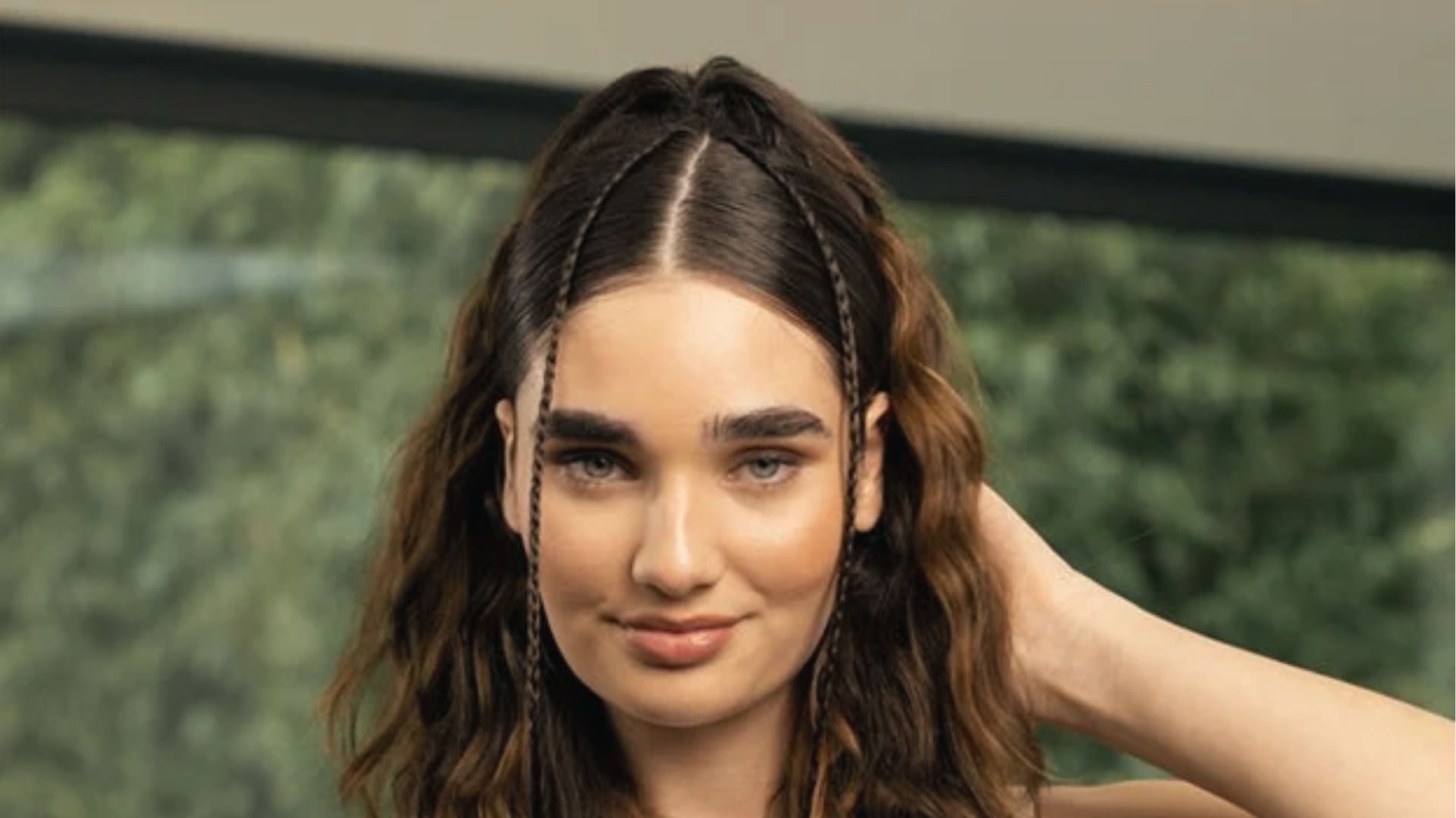 Wavy half up half down style with mini braids framing face, center part, and soft volume