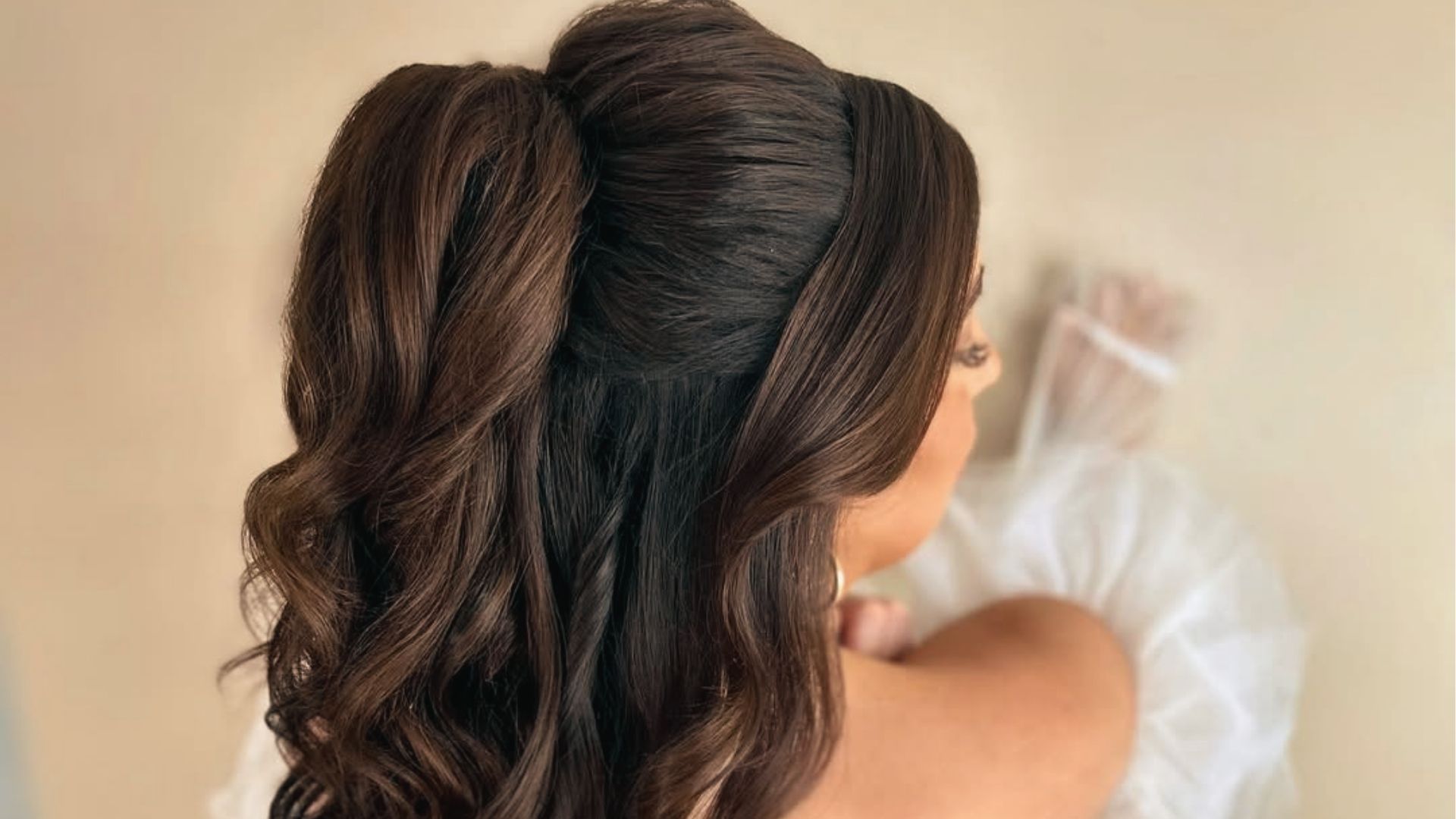 Half up half down black hairstyle with voluminous crown, soft curls, and white veil