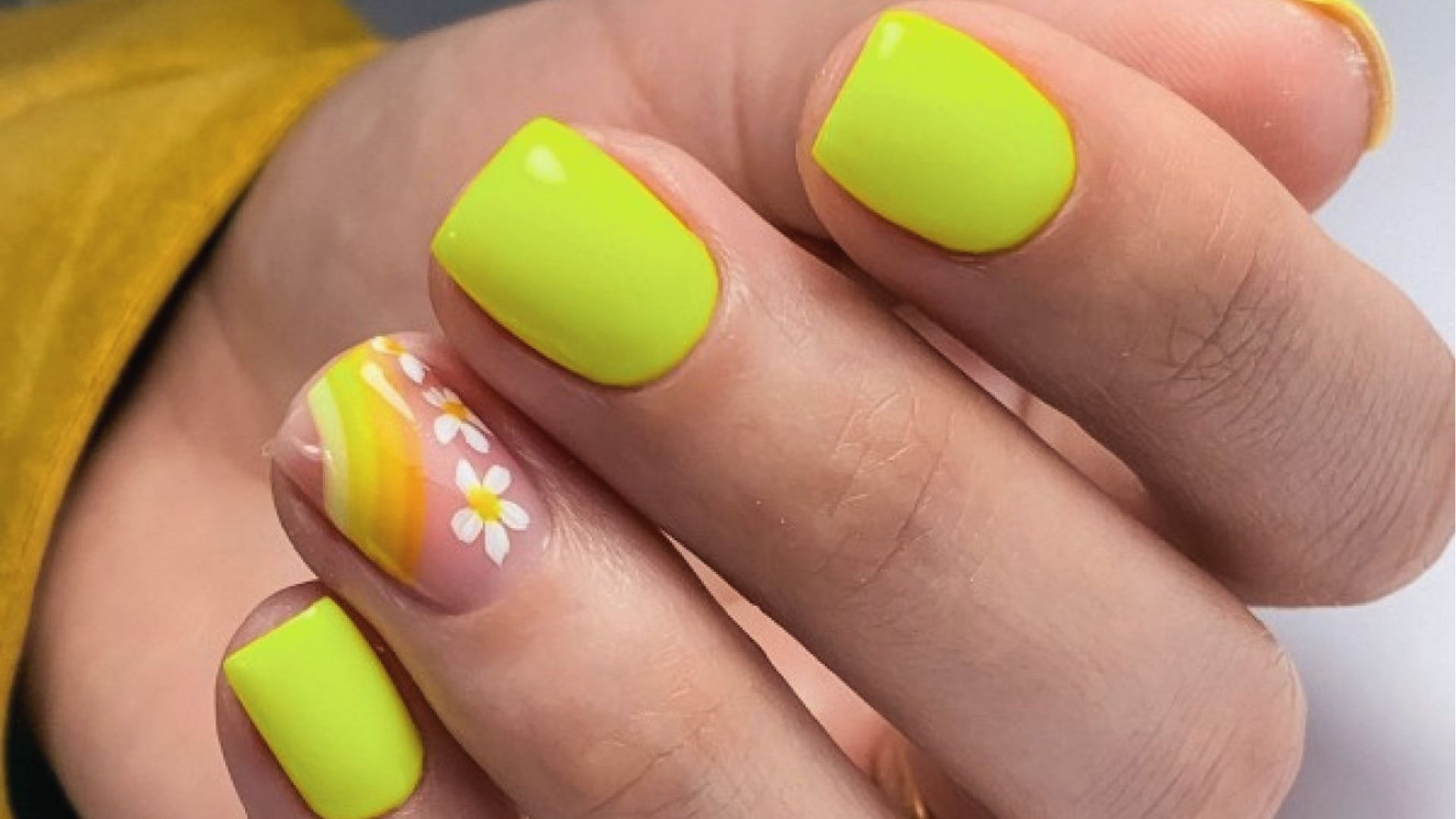 Short square nails in neon yellow with white daisy art and orange stripes on accent nail, dainty
