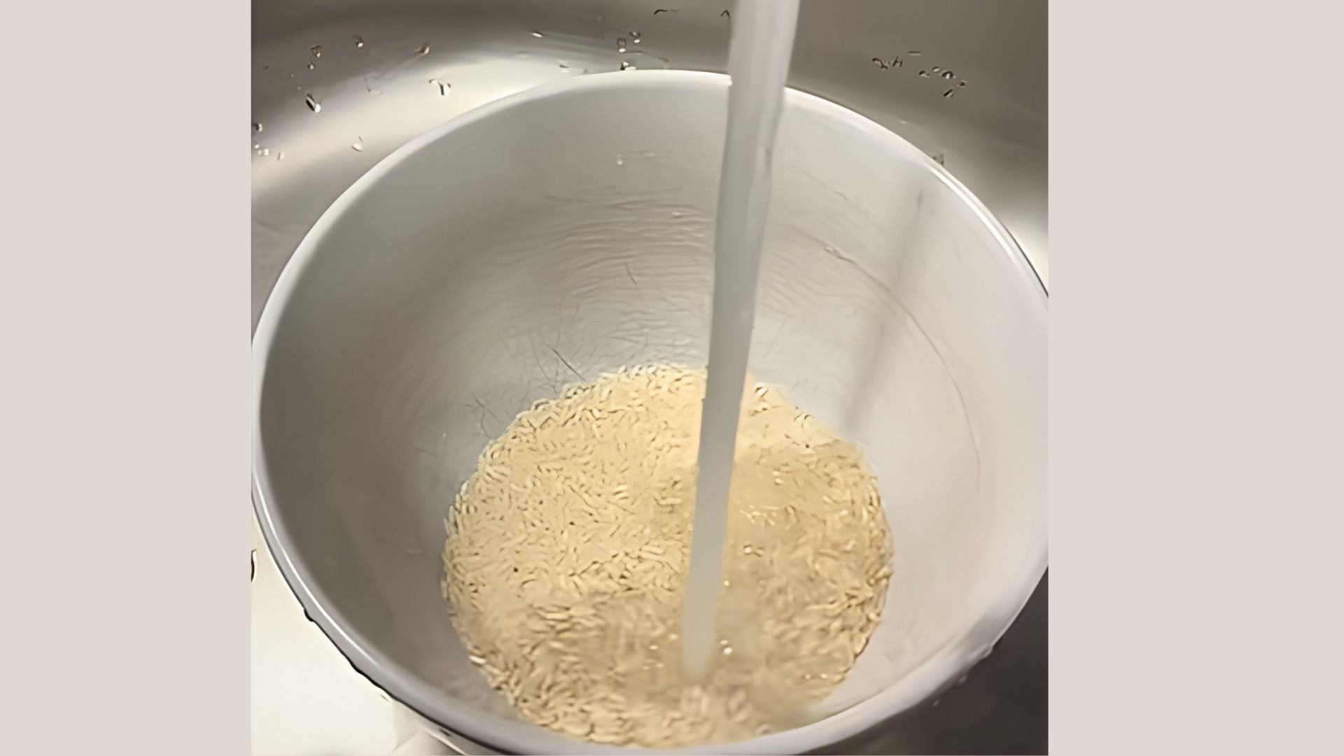 Rice being rinsed in a bowl under running water to clean it before making rice water for hair