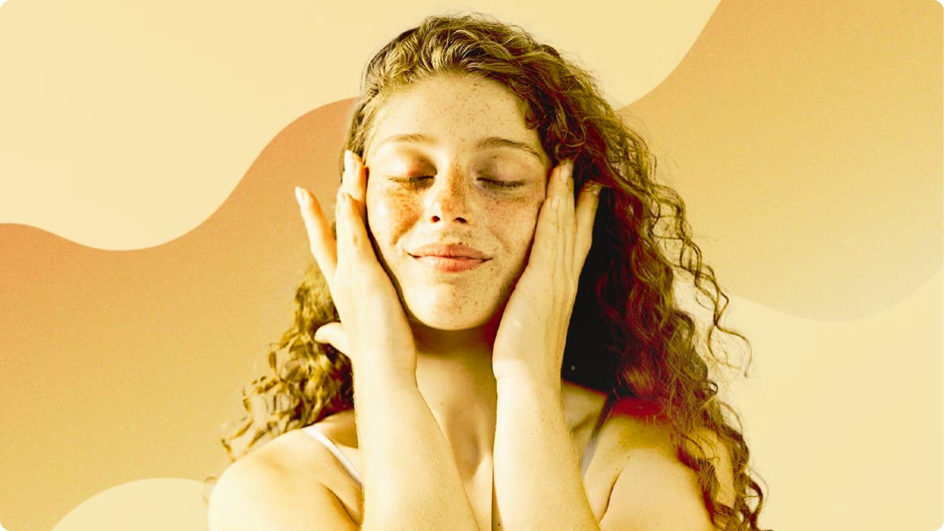 Smiling woman with Combination Skin and freckles gently touching her clear, post-facial skin.