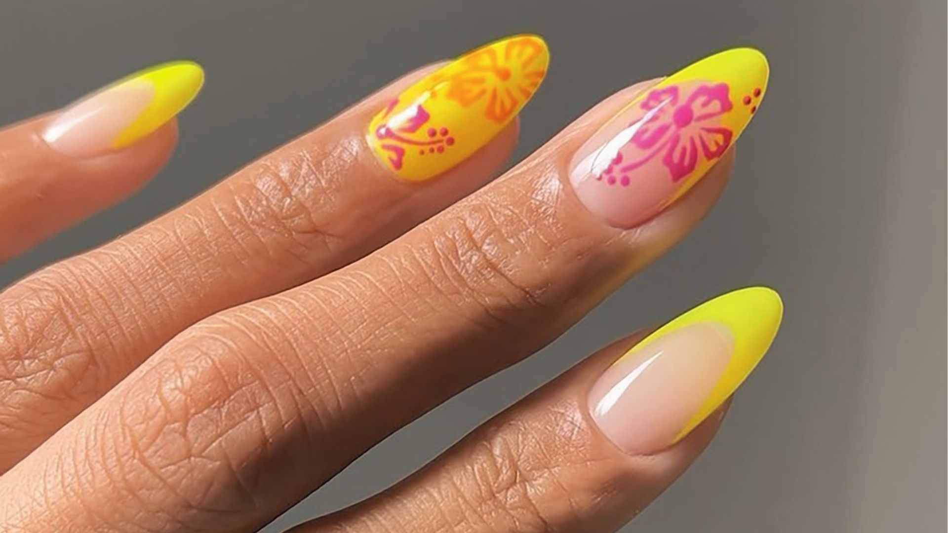 Long almond nails with neon yellow French tips and pink tropical flower art on nude base, glossy