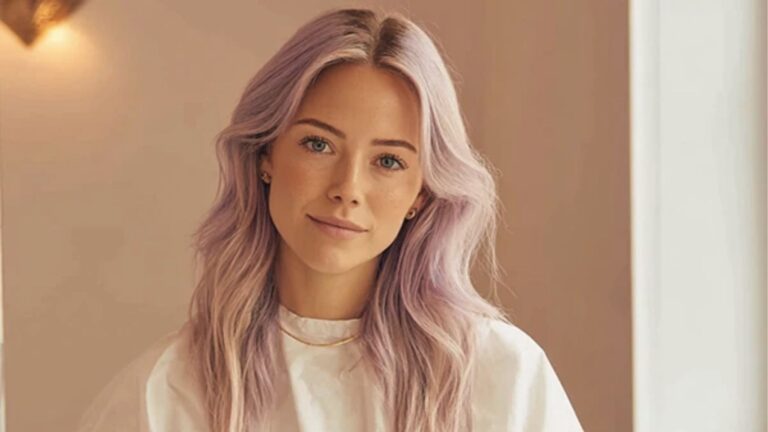 Woman with long wavy lavender hair in white top.