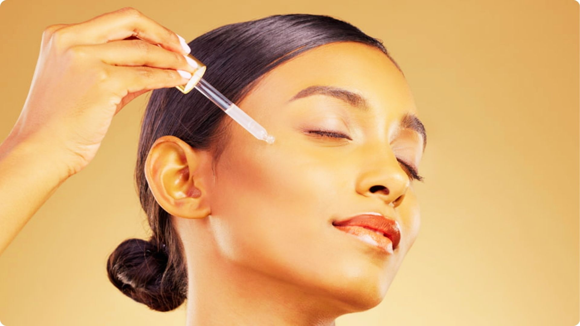A woman with dark hair applies Niacinamide from a dropper onto her cheek with eyes closed.