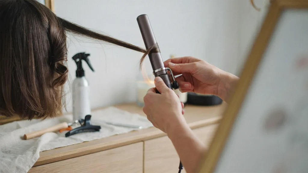 Person releasing curled short hair and letting it cool in hand for longer hold.