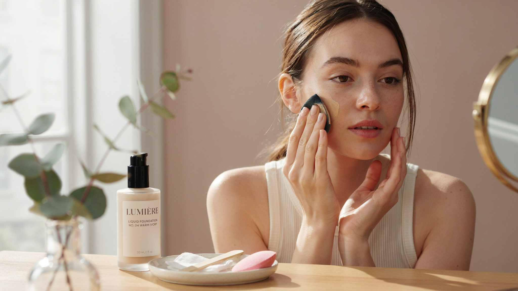 Woman blending foundation onto her face before applying concealer for an even makeup base.