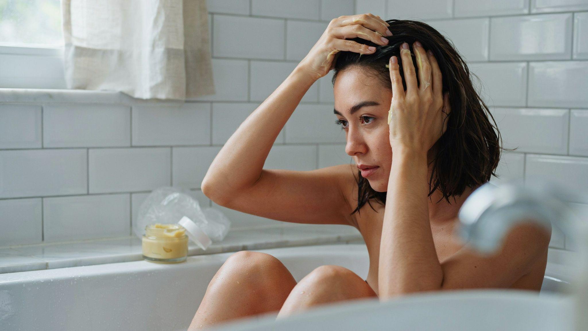 Person applying vitamin C paste to hair for color removal.