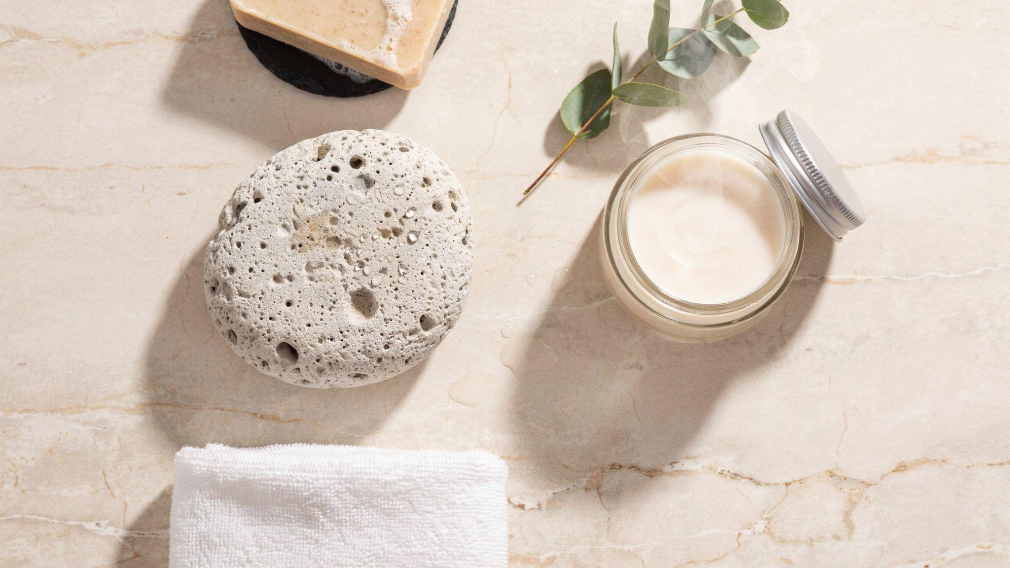 Essential pumice stone skincare supplies arranged neatly with towel, soap, water, and moisturizer