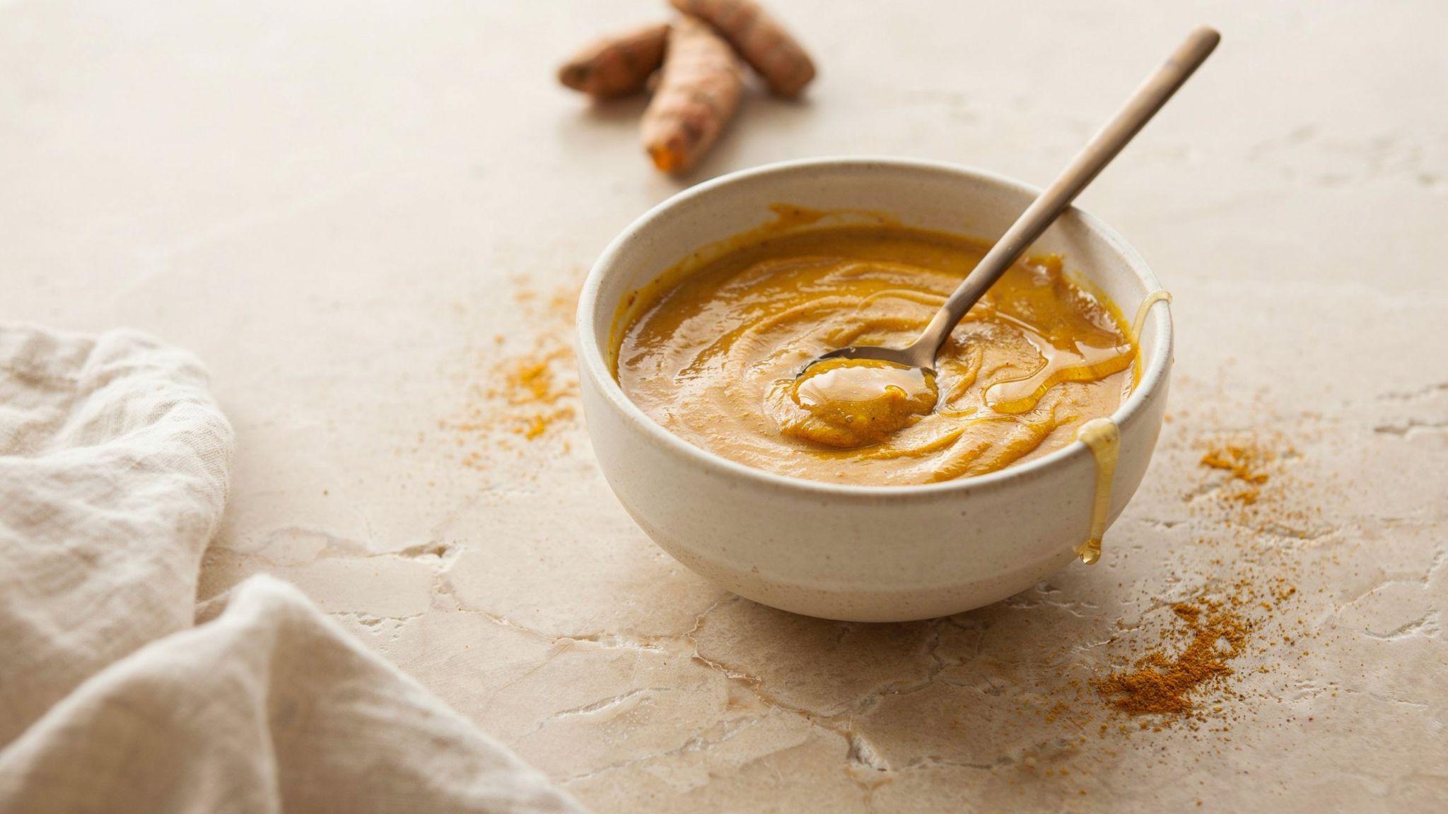 Close-up of turmeric paste in a bowl used for natural skin brightening and exfoliation.