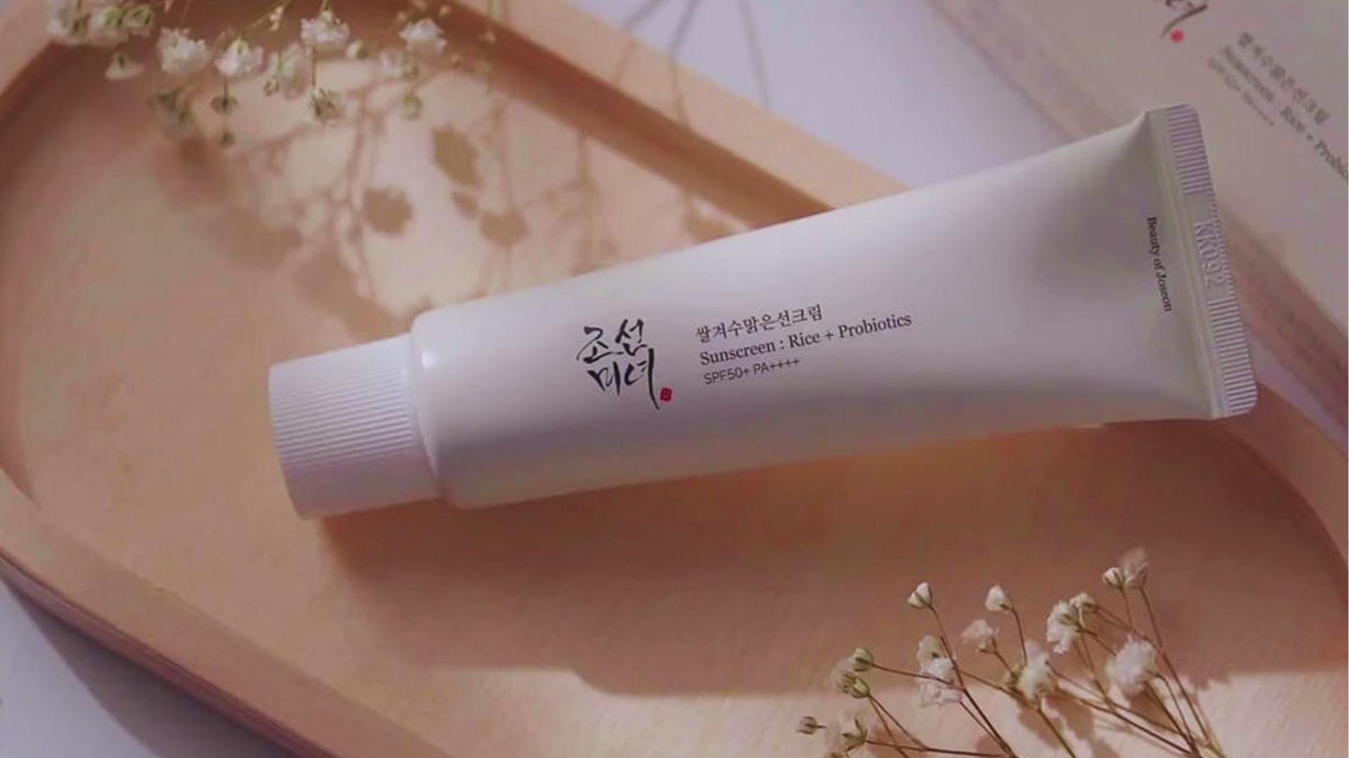 Beauty of Joseon Sunscreen Rice + Probiotics SPF50+ PA++++ tube lies on a wooden tray with delicate baby’s breath flowers beside it.