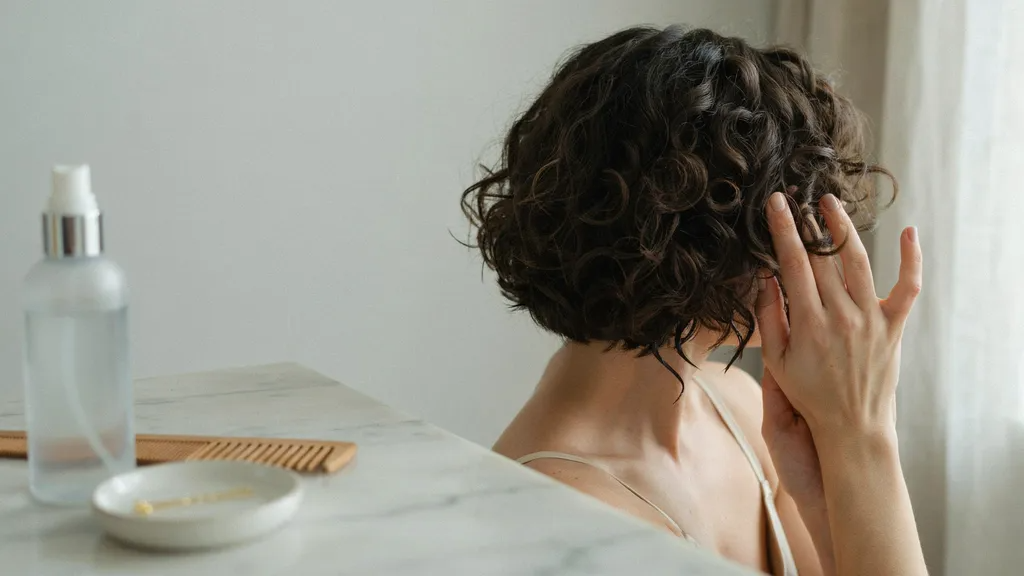 Person finishing short curls by separating them and setting with hairspray.