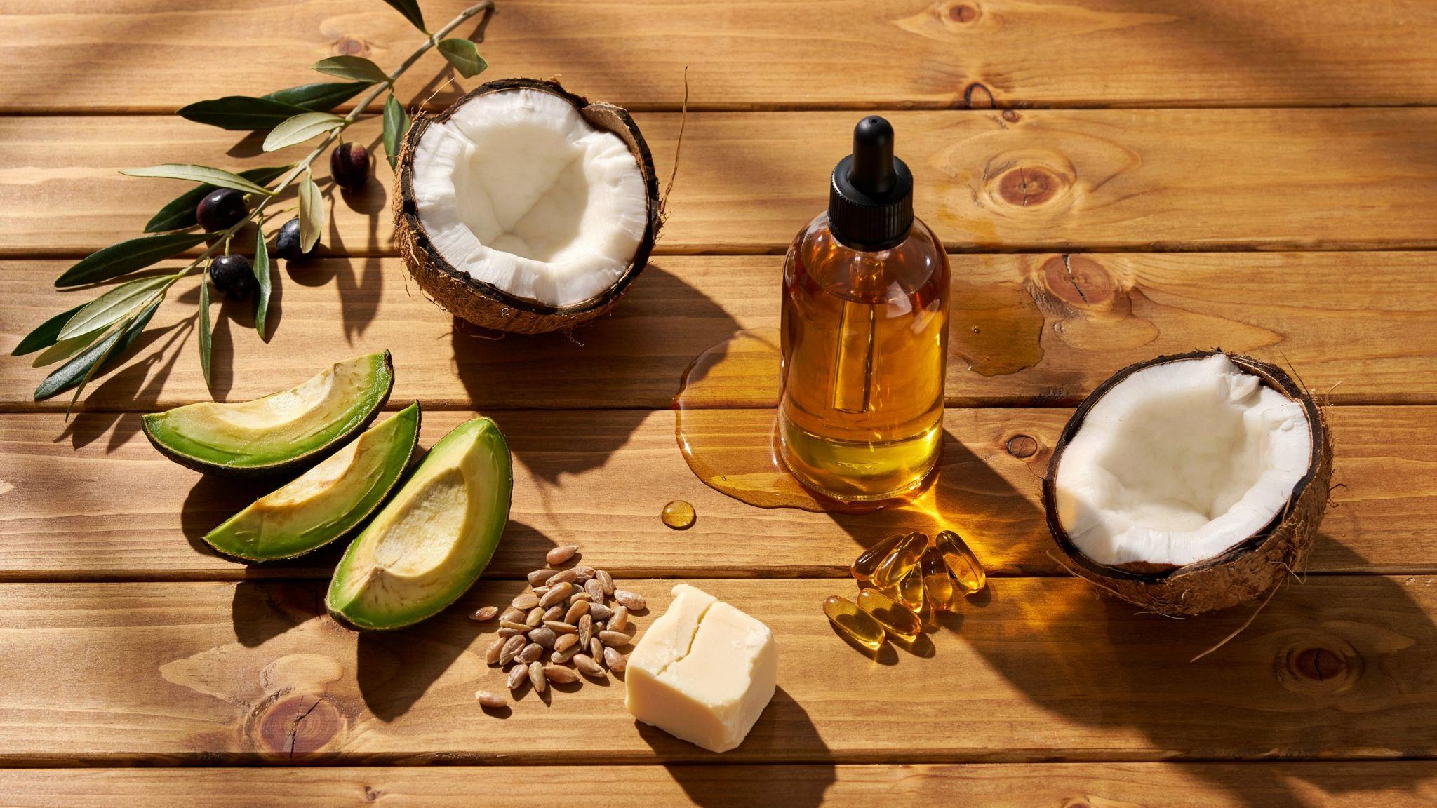 Natural tanning oil ingredients with coconut, avocado, olive oil, and skincare essentials displayed.
