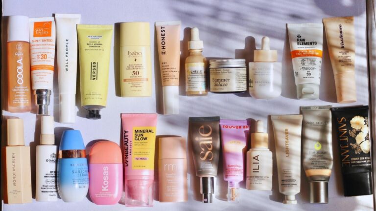 Flat lay of 20 clean beauty tinted moisturizers with SPF from brands like COOLA, Kosas, ILIA, Saie, and Tower 28.