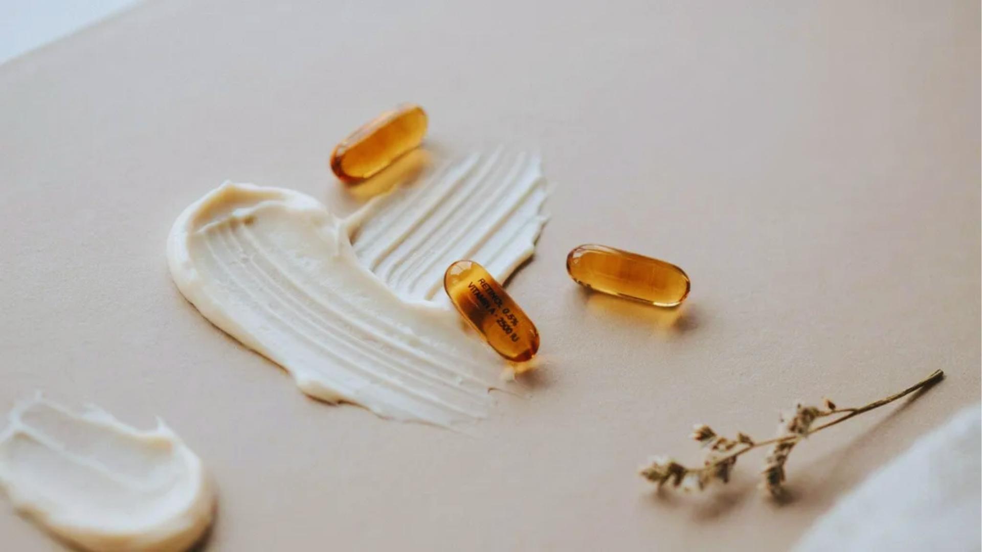 Retinol cream texture with vitamin A capsules displayed on a clean surface representing skin renewal concept.