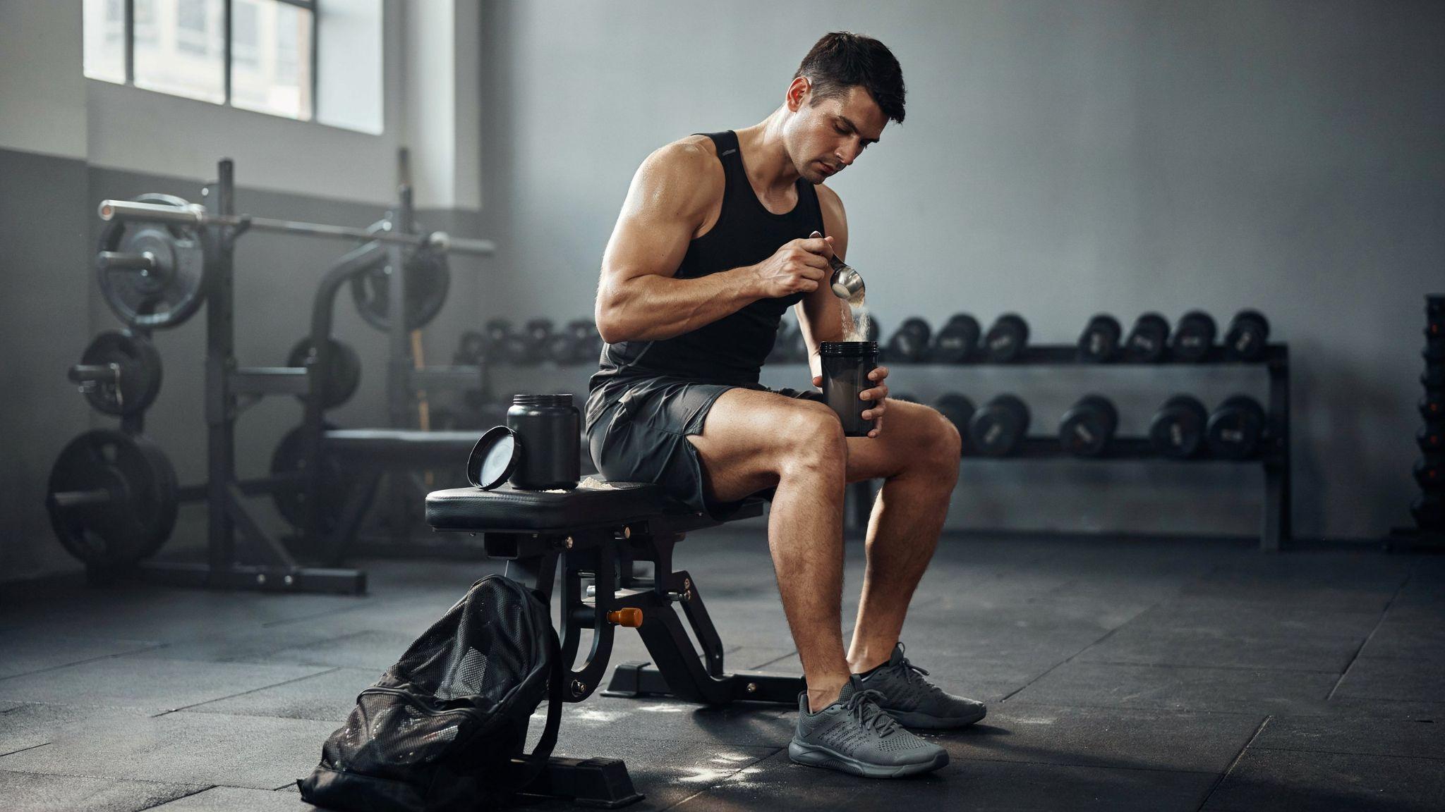 "Athlete preparing creatine drink in gym shaker bottle in realistic fitness setting"
