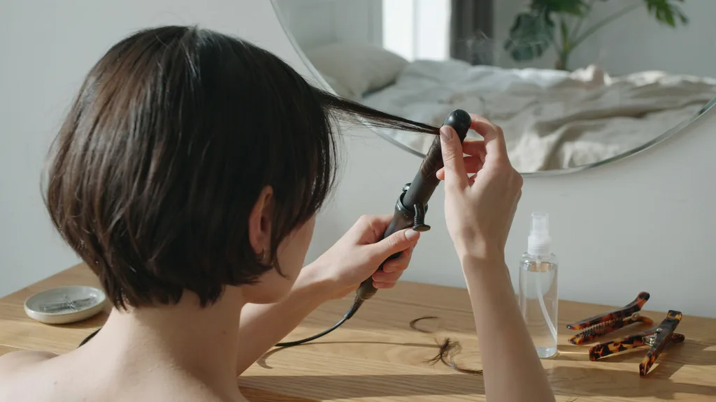 Person struggling to curl short hair showing difficulty compared to longer hair styling.