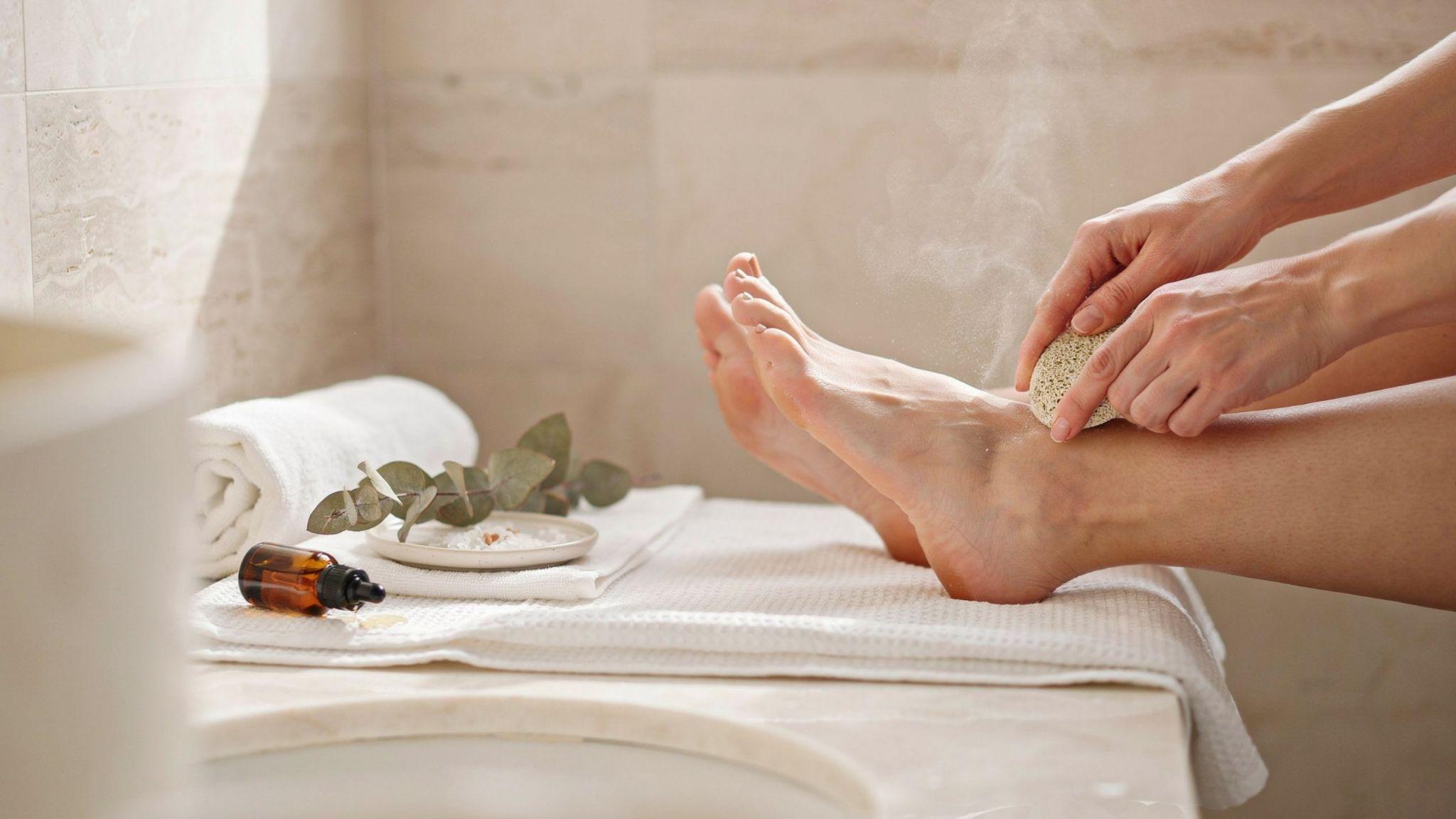 Smooth heels receiving pumice stone exfoliation in bright spa setting with healthy skin texture