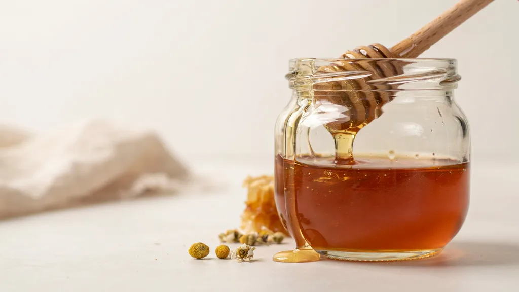 Close-up of a jar of honey used as a natural moisturizing skincare remedy.