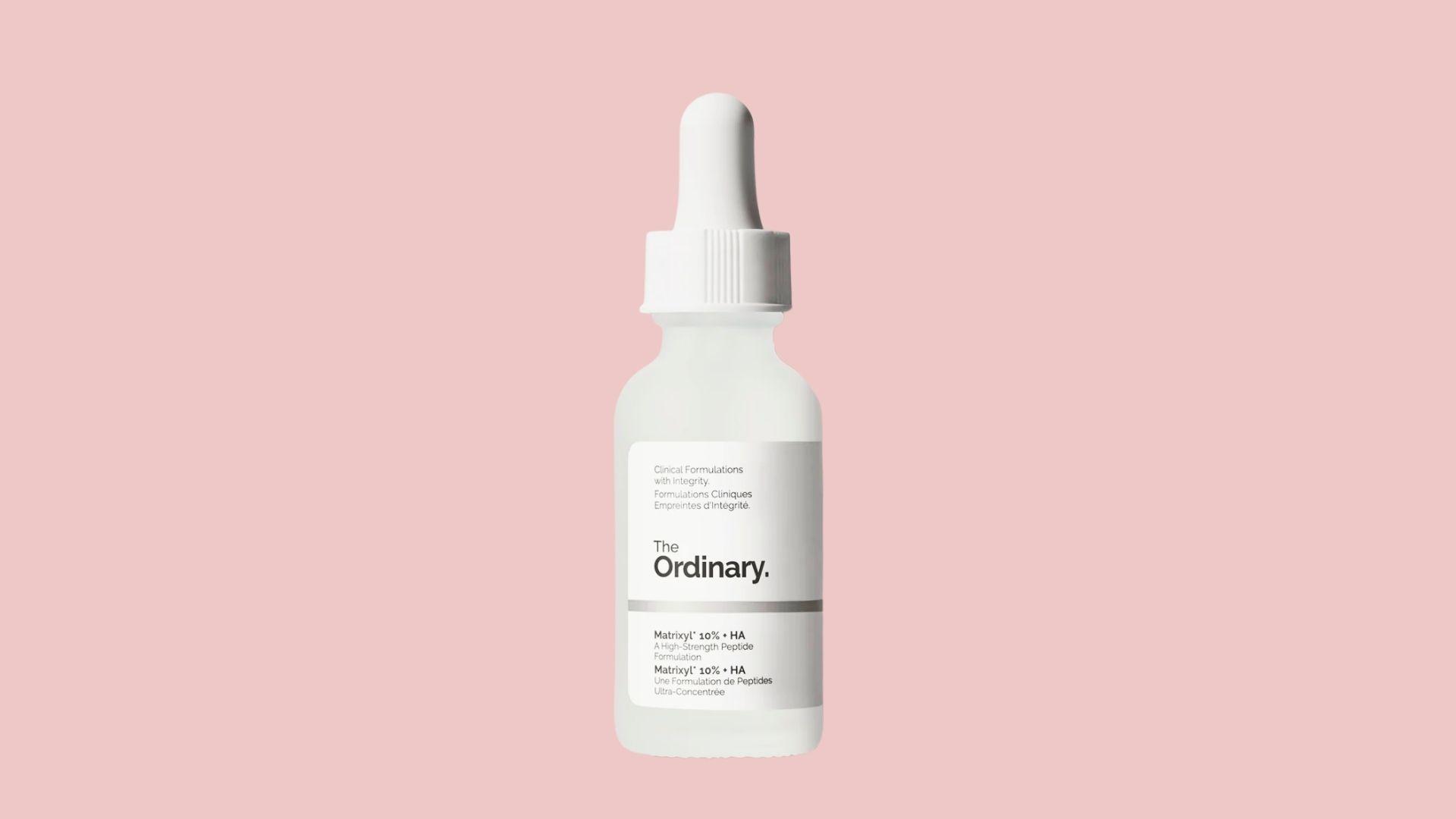 The Ordinary Matrixyl 10% + HA white glass dropper bottle with silver label, minimalist skincare serum, pink background