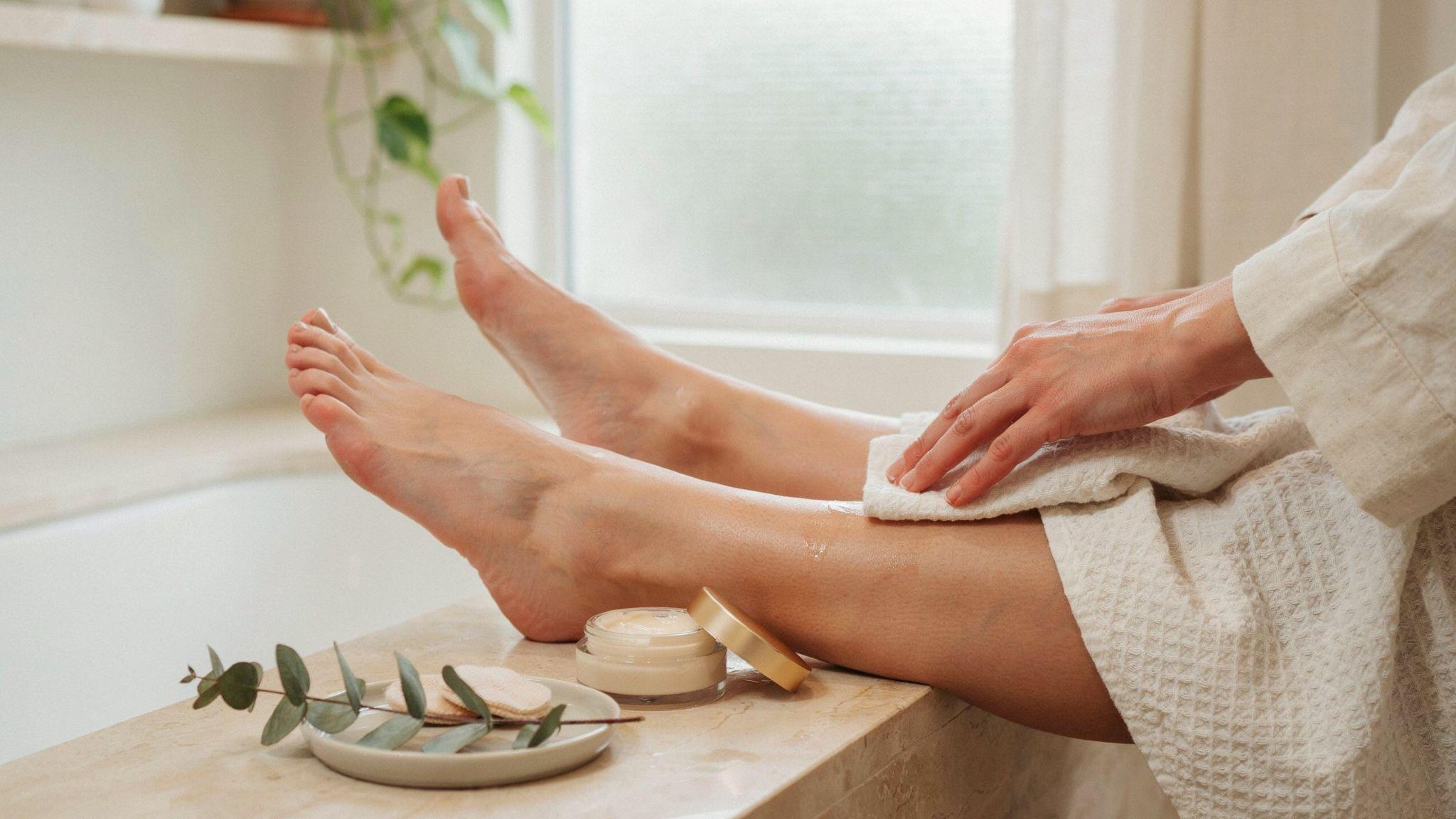 Smooth feet being moisturized after exfoliation with towel and skincare products