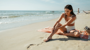 woman applying coconut oil on skin at sunny beach highlighting natural glow and sun exposure during outdoor tanning session.