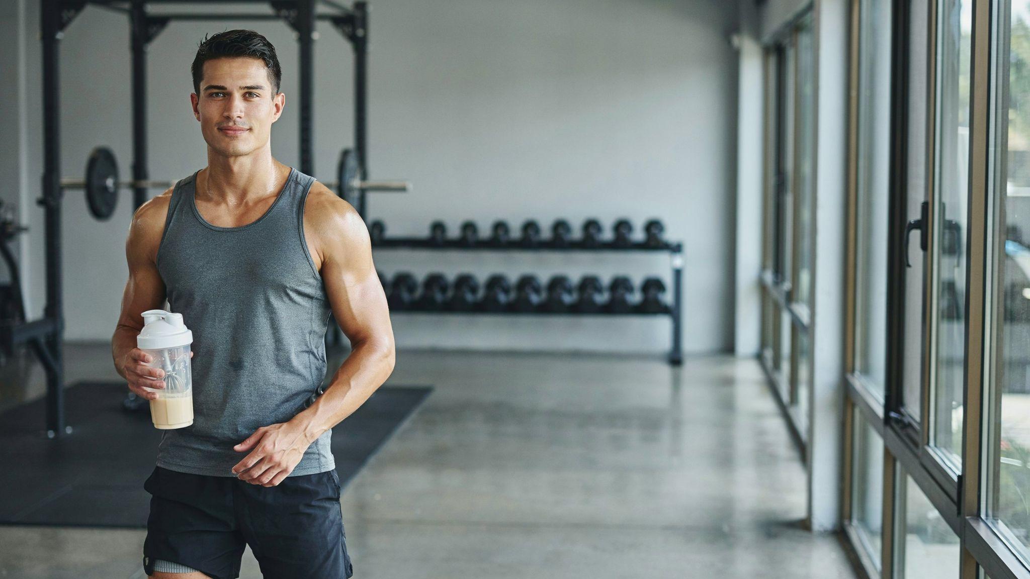 "Confident person in gym holding supplement shaker bottle in realistic fitness setting"