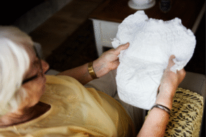 An older woman holding a piece of paper, looking thoughtfully at the document in her hands.