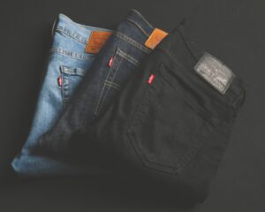 Three pairs of jeans displayed on a black background, showcasing different styles and colors.