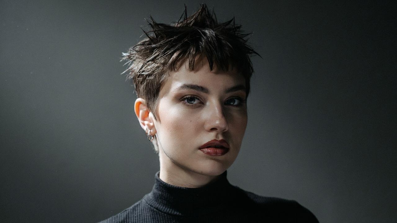 Woman with bold spiky bangs styled upward.