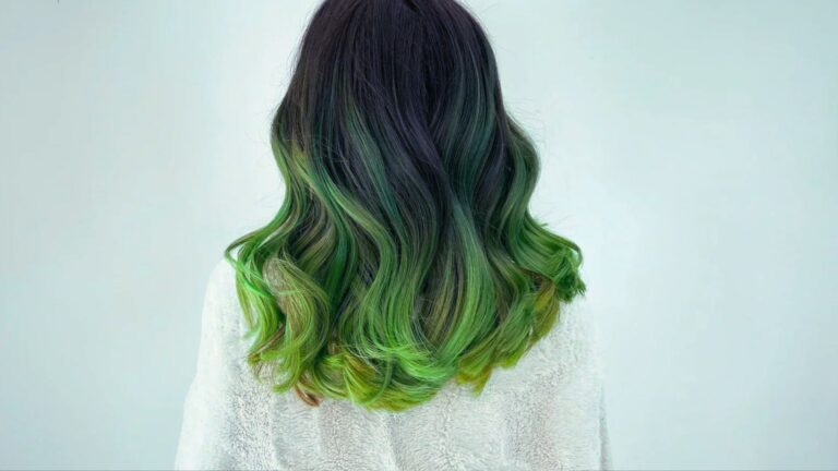 Wavy, shoulder-length blonde hair showing a prominent green tint throughout the mid-lengths and ends.