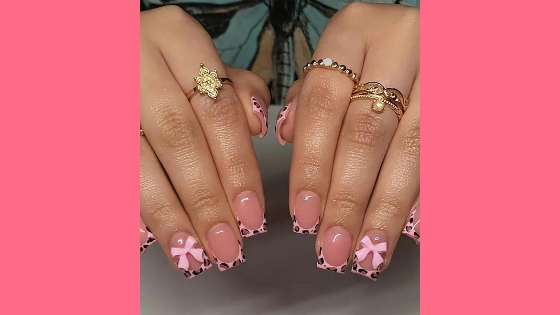Long square pink nails with leopard French tips, 3D bows, multiple gold rings, sheer base