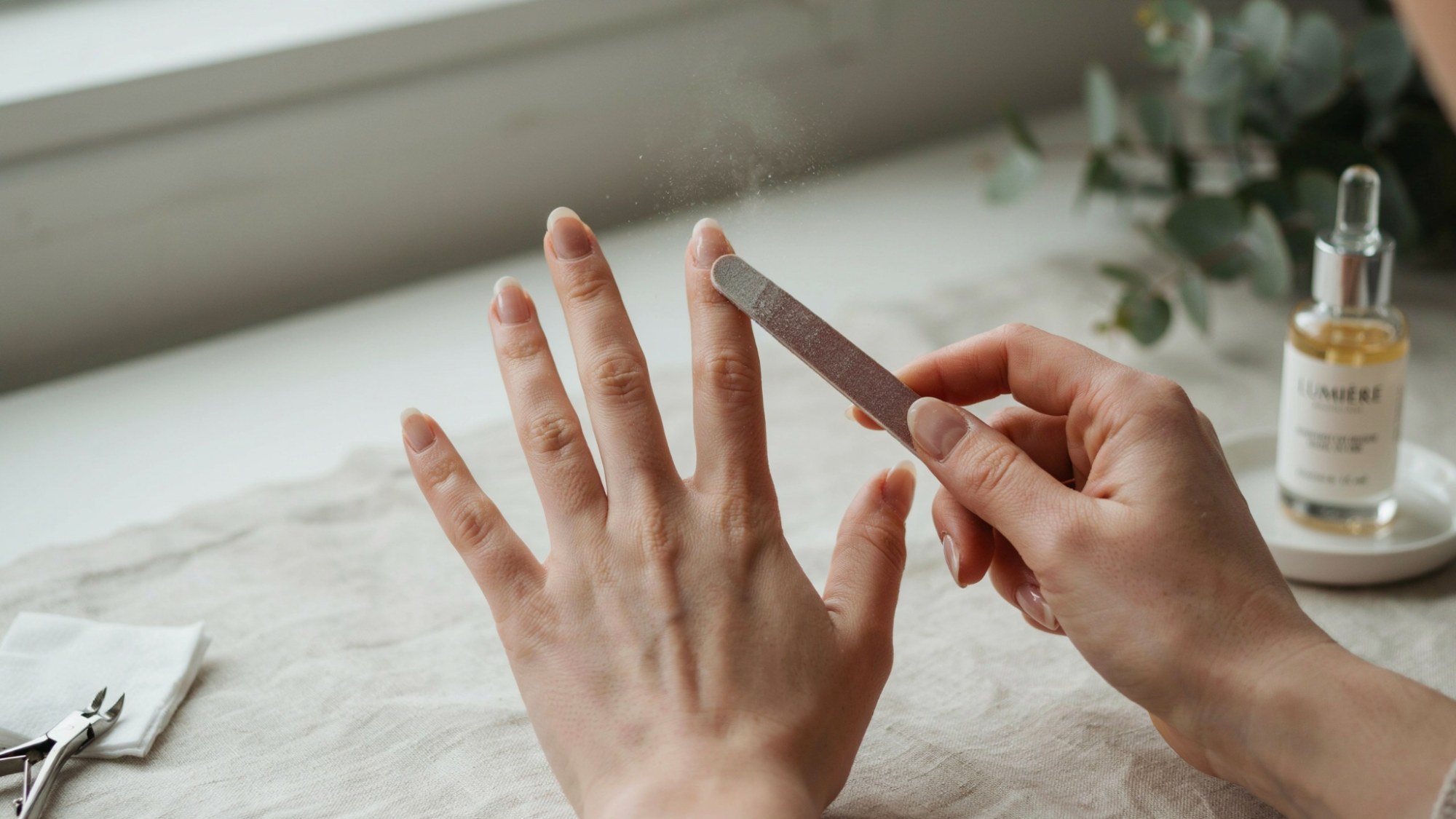 Filing natural nails into an almond shape.