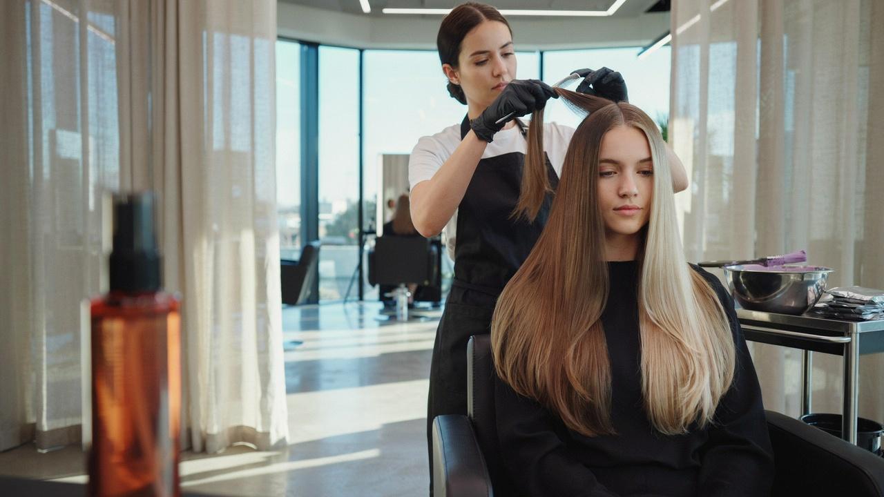 Professional stylist performing a double process color transformation from dark brown to platinum blonde.