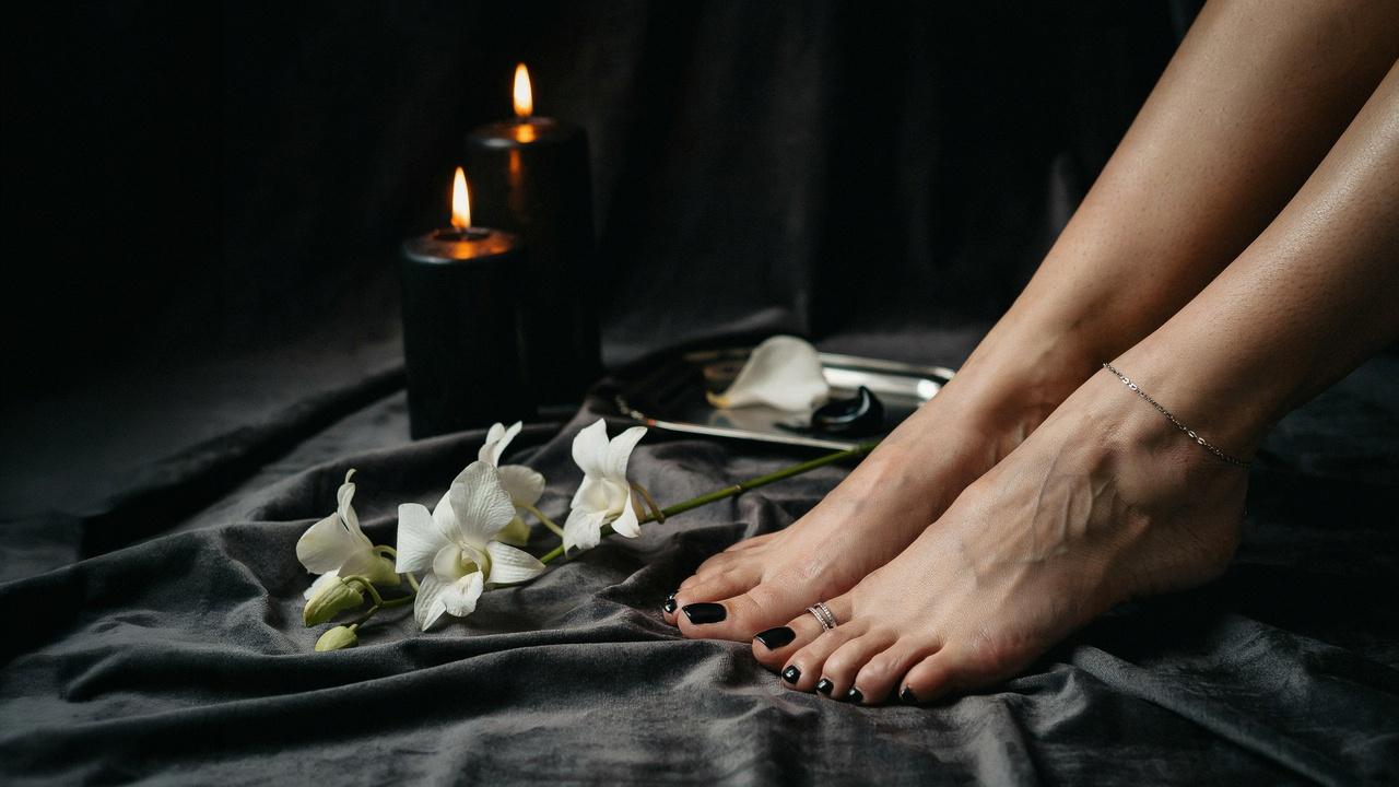 Elegant feet showcasing a glossy black pedicure in a chic and luxurious spa-inspired setting.