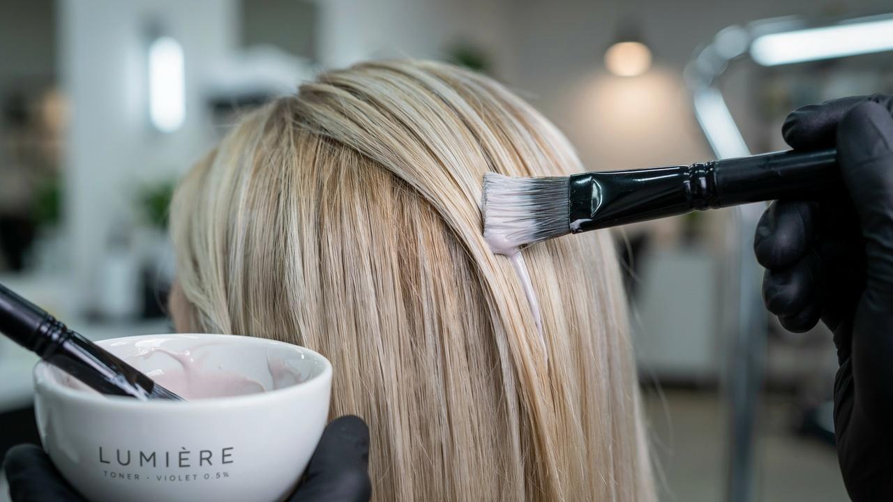 Hair toner being applied to lighten and neutralize brassy tones after bleaching.
