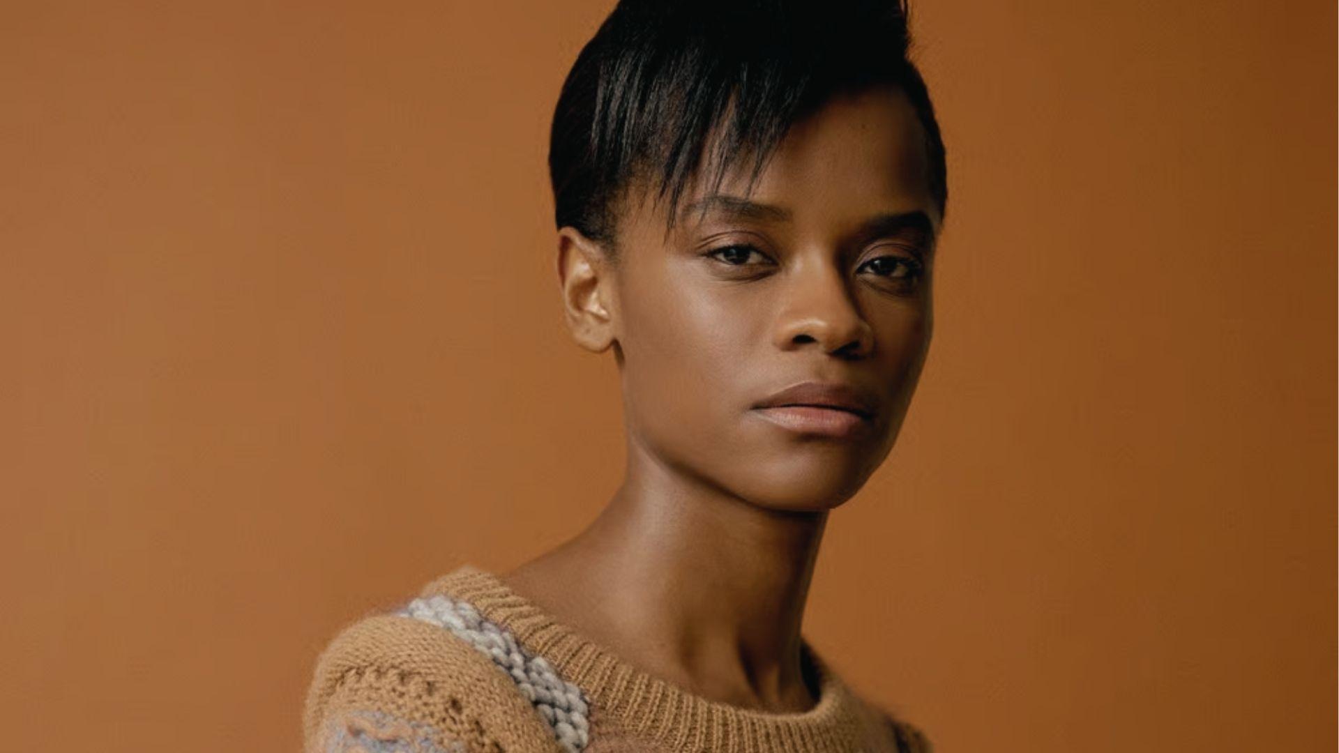 Woman with Letitia Wright-Influenced Pixie, side-swept bangs, knit sweater, neutral backdrop