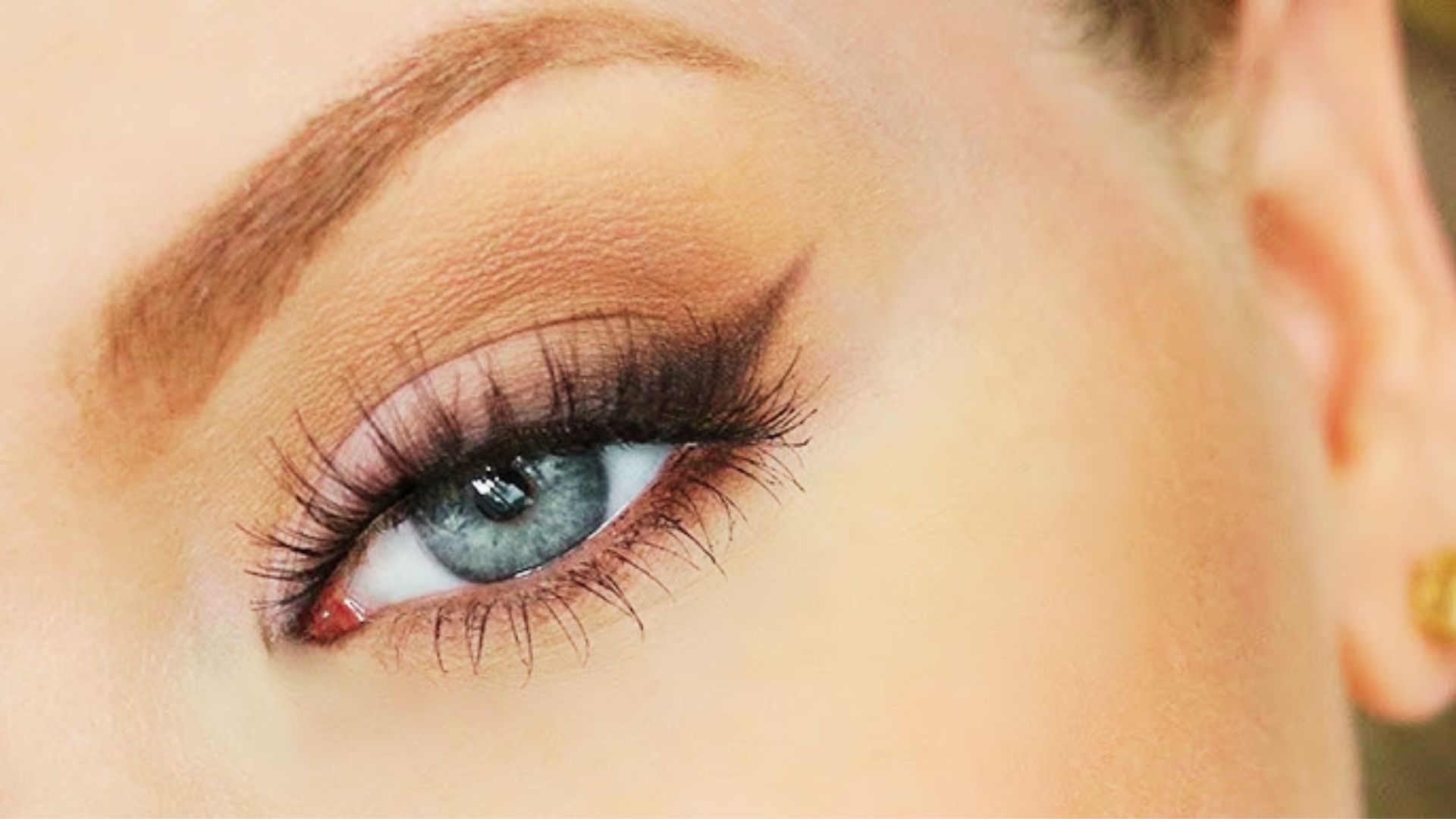 Close-up of a blue eye with soft matte brown eyeshadow, smudged liner, and long lashes for a romantic wedding look.